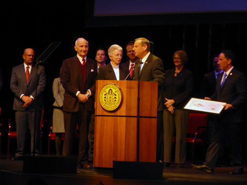 Bob Filner at right of lecturn congratulates philanthropists Ernest and Evelyn Rady as Council President Todd Gloria brings certificate and rest of City Council looks on