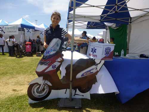 Felicia Saltzbart, executive director of United Hatzalah of Israel, stands by a cutout of an "ambu-cycle"