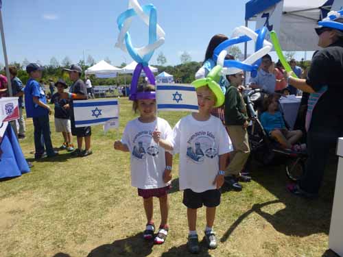 Twins Eden and Alexander Cohen, 5,  wear Magen David balloon hats and wave Israeli flags at Yom Ha'Atzma'ut celebration